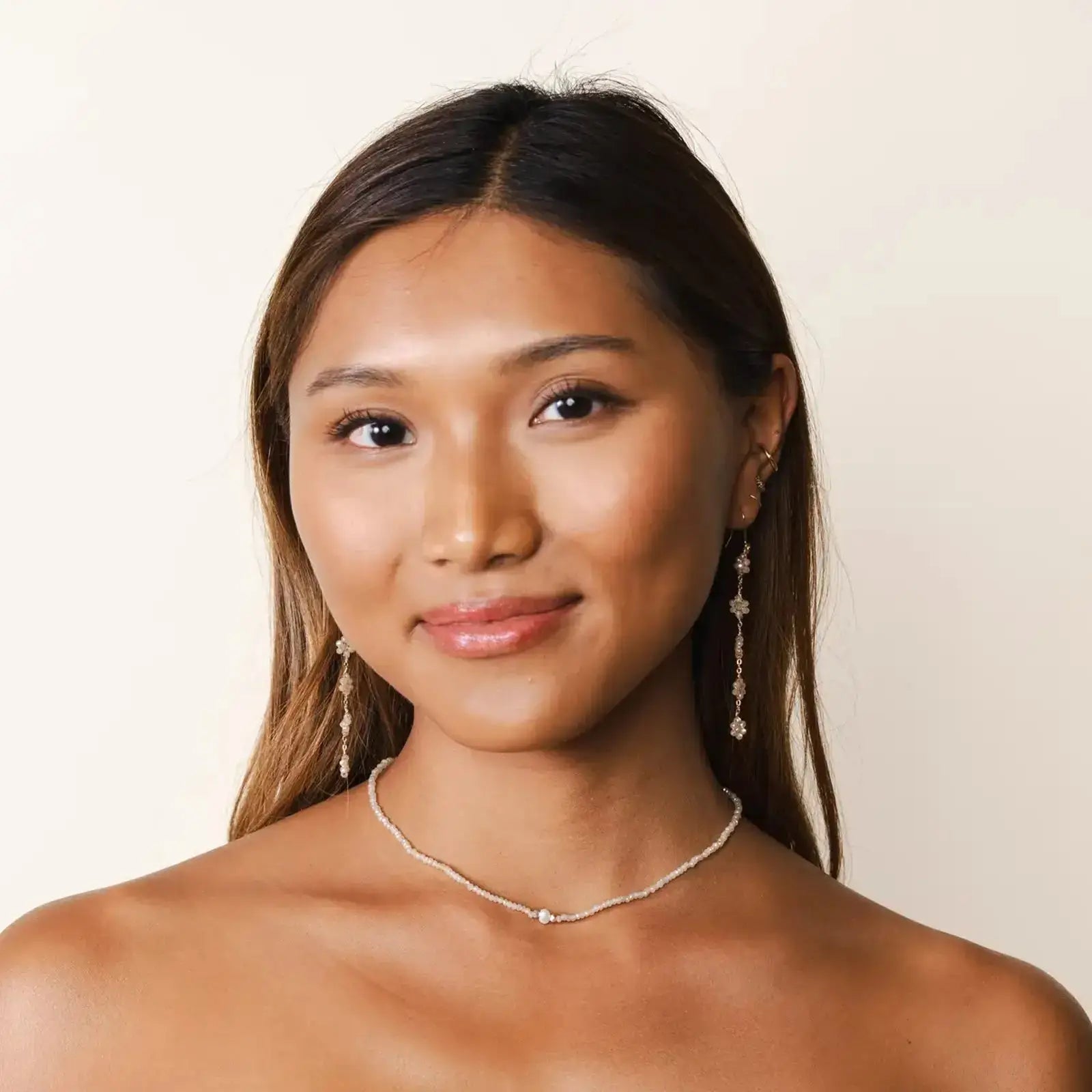 boho flower dangle earrings by lotus and luna on model wearing a pearl necklace