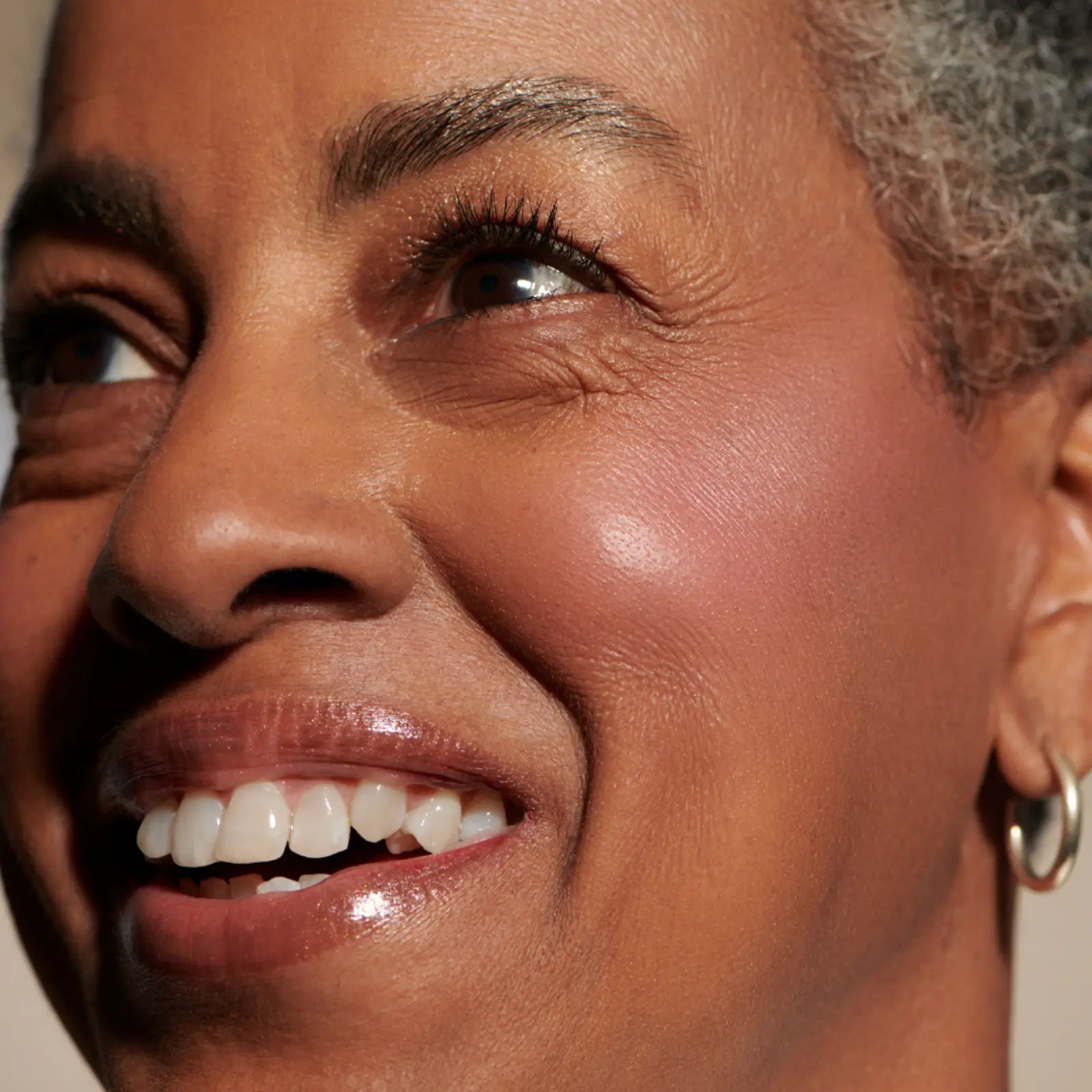 a woman with dark skin wearing minori cream blush in sweet pea Pink on her cheeks