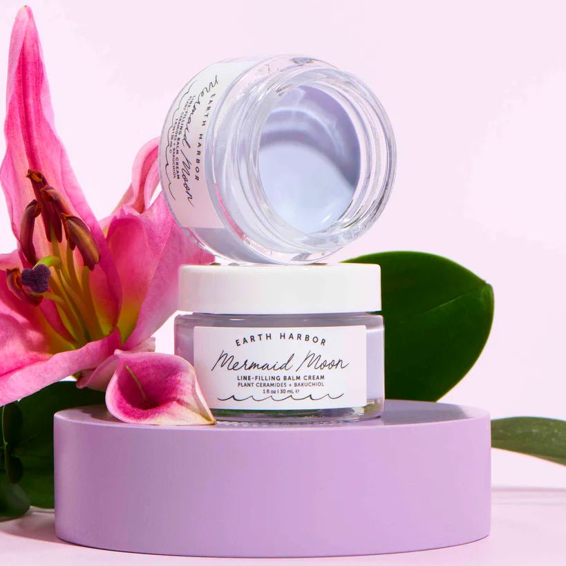 Earth Harbor Mermaid Moon Line-Filling Balm Cream in a clear glass jar with a white lid, displayed on a lavender pedestal.