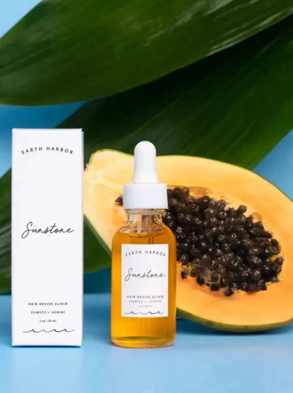 A bottle of earth harbor sunstone hair revive elixir next to cut fruit 
