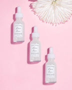 three 1 oz bottles of  earth lharbor luna rain night serum on a pink background
