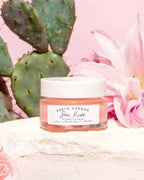Earth Harbor SEA KISS lip balm jar displayed with prickly pear cactus and pink flowers, highlighting its natural ingredients.