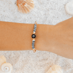 Evil Eye Protection Bracelet with yellow gold round beads and black and white evil eye shown on a woman's wrist