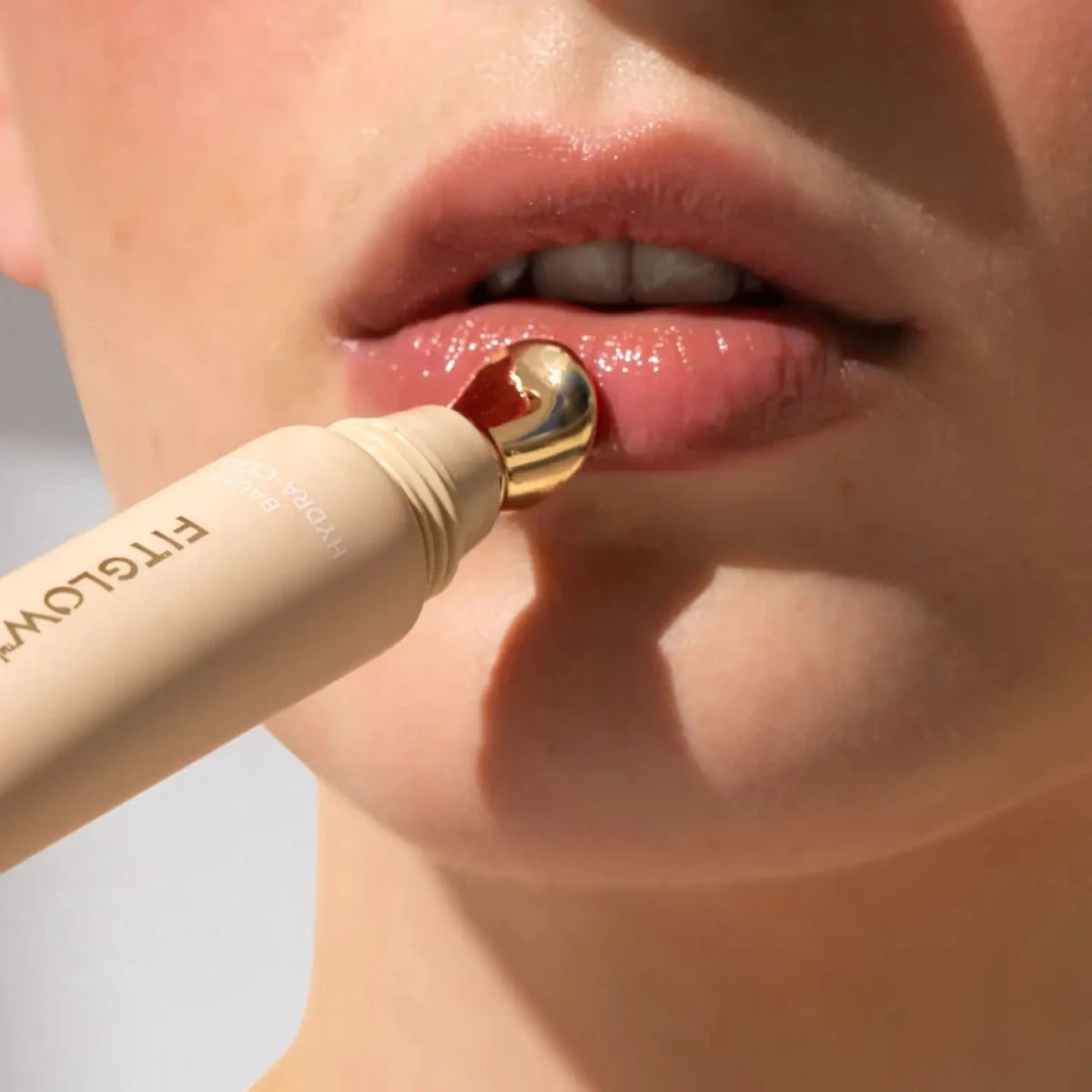 Fitglow Hydra Balm in Rosewood, a warm pink beige applied on lips.