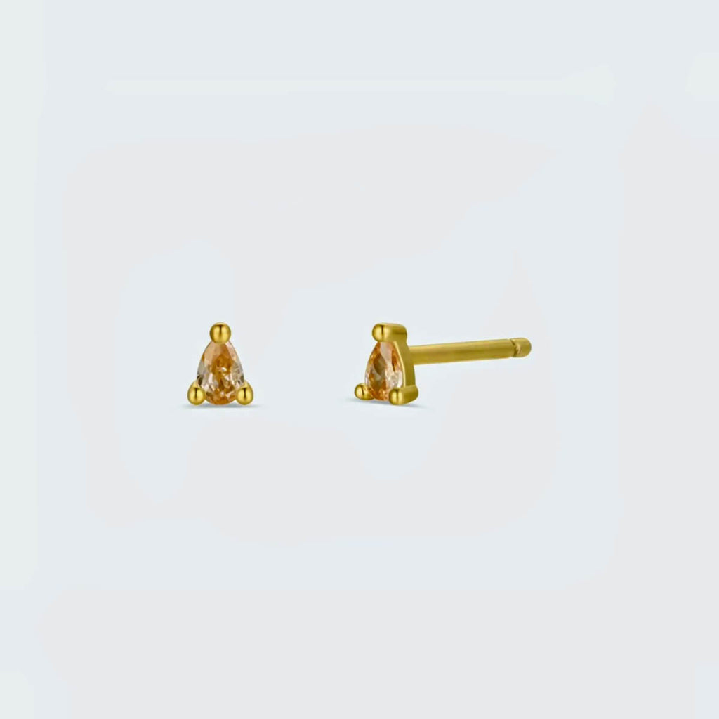 Gold stud earrings with pink champagne gemstones on a light gray background