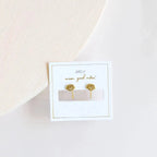 a pair of gold lotus flower earrings sitting on a table