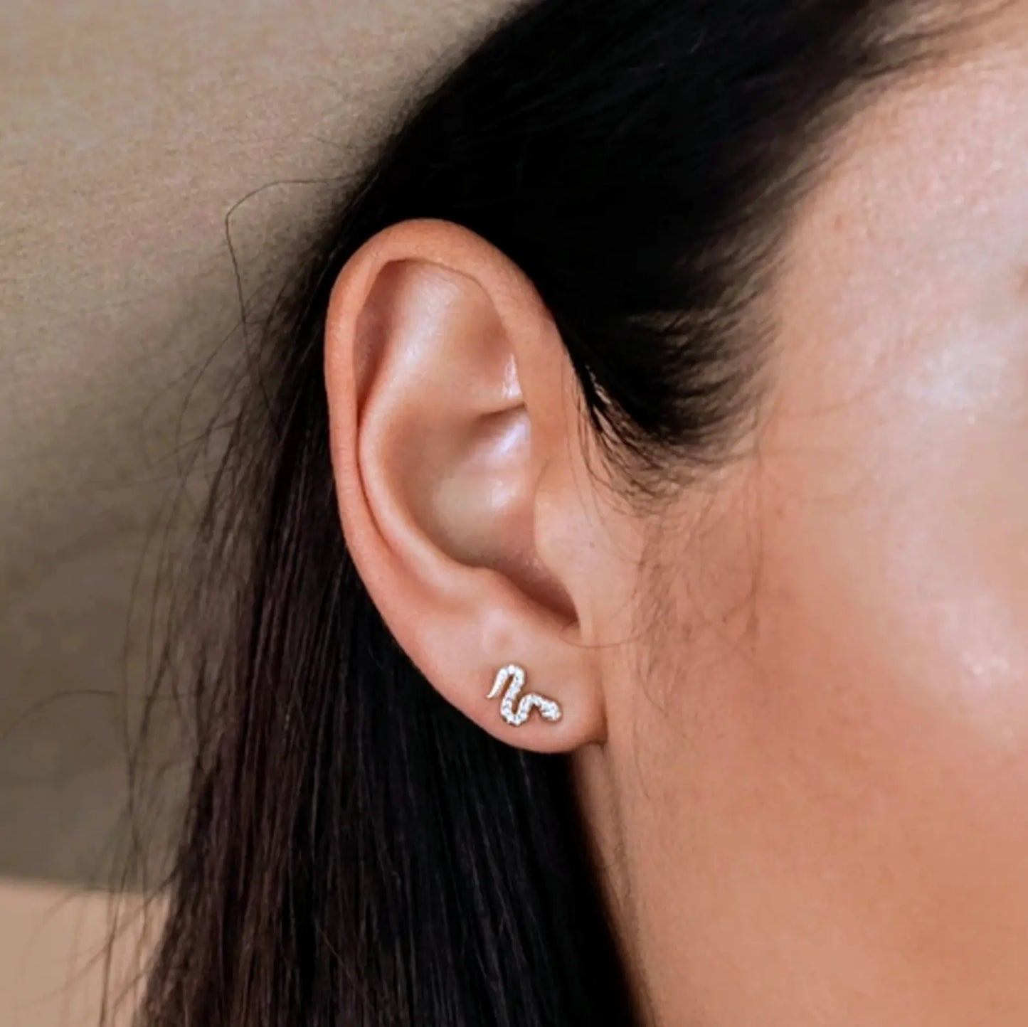 a close up of a woman wearing snake earrings