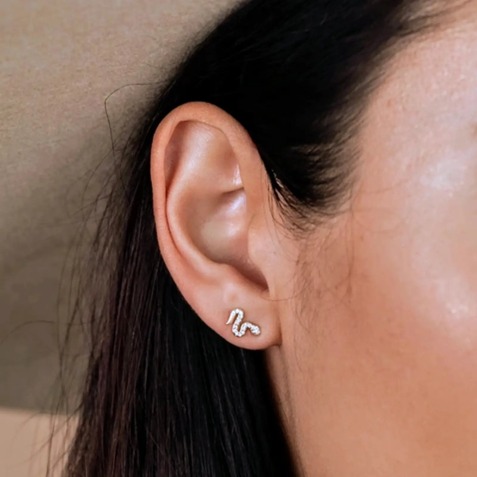 a close up of a woman wearing snake earrings