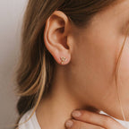 Yellow gold evil-eye stud earrings with dangling green amazonite gemstone surrounded by white cubic zirconia accent stones.