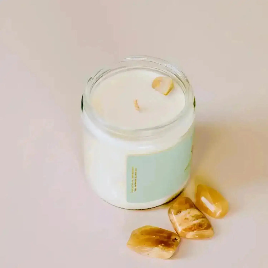 a glass jar with a candle and some moonstone gemstones
