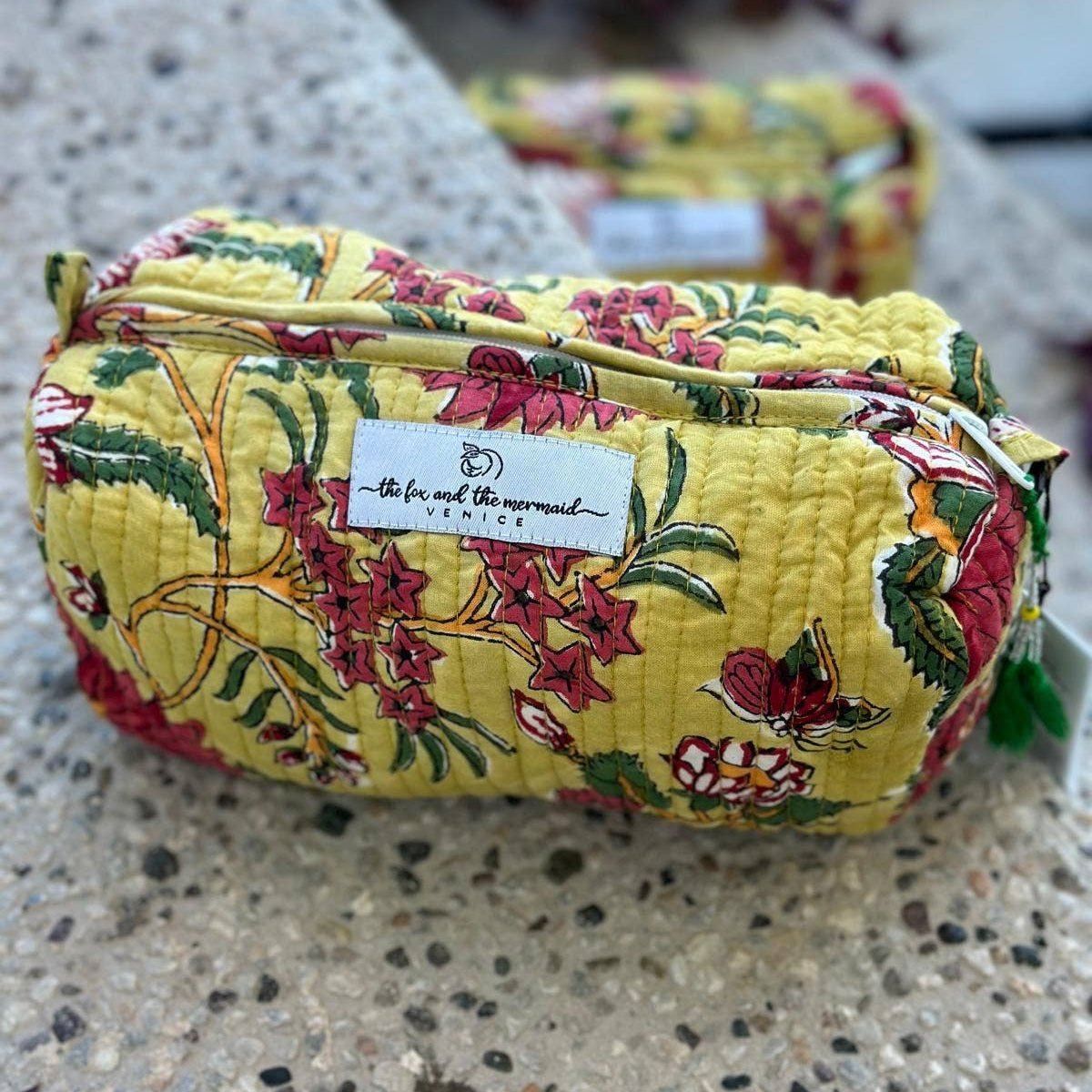 Yellow floral-patterned cosmetic pouch on a concrete surface