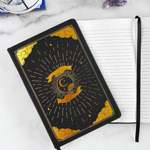 Black notebook for mindfulness journey with gold celestial design on a white surface