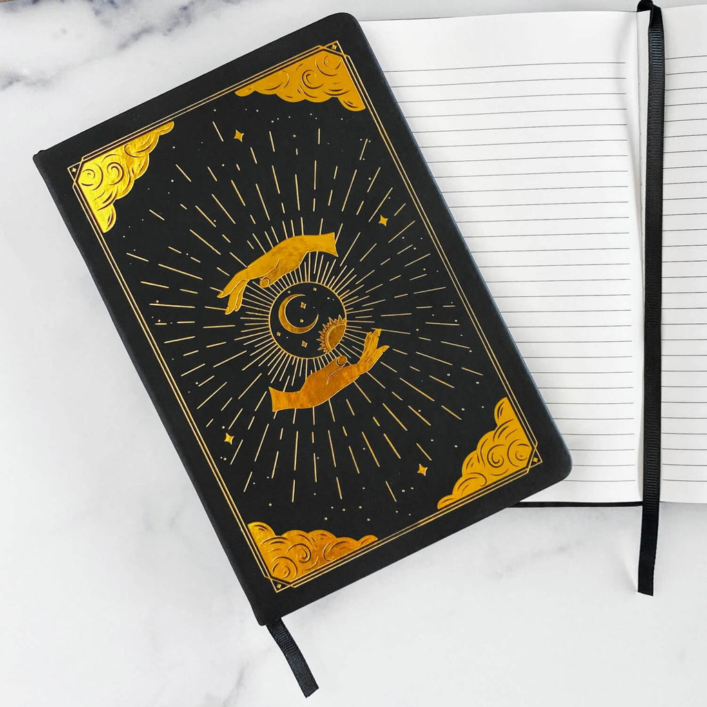 Black intention and mindfulness journal and notebook with gold celestial design on a white marble surface