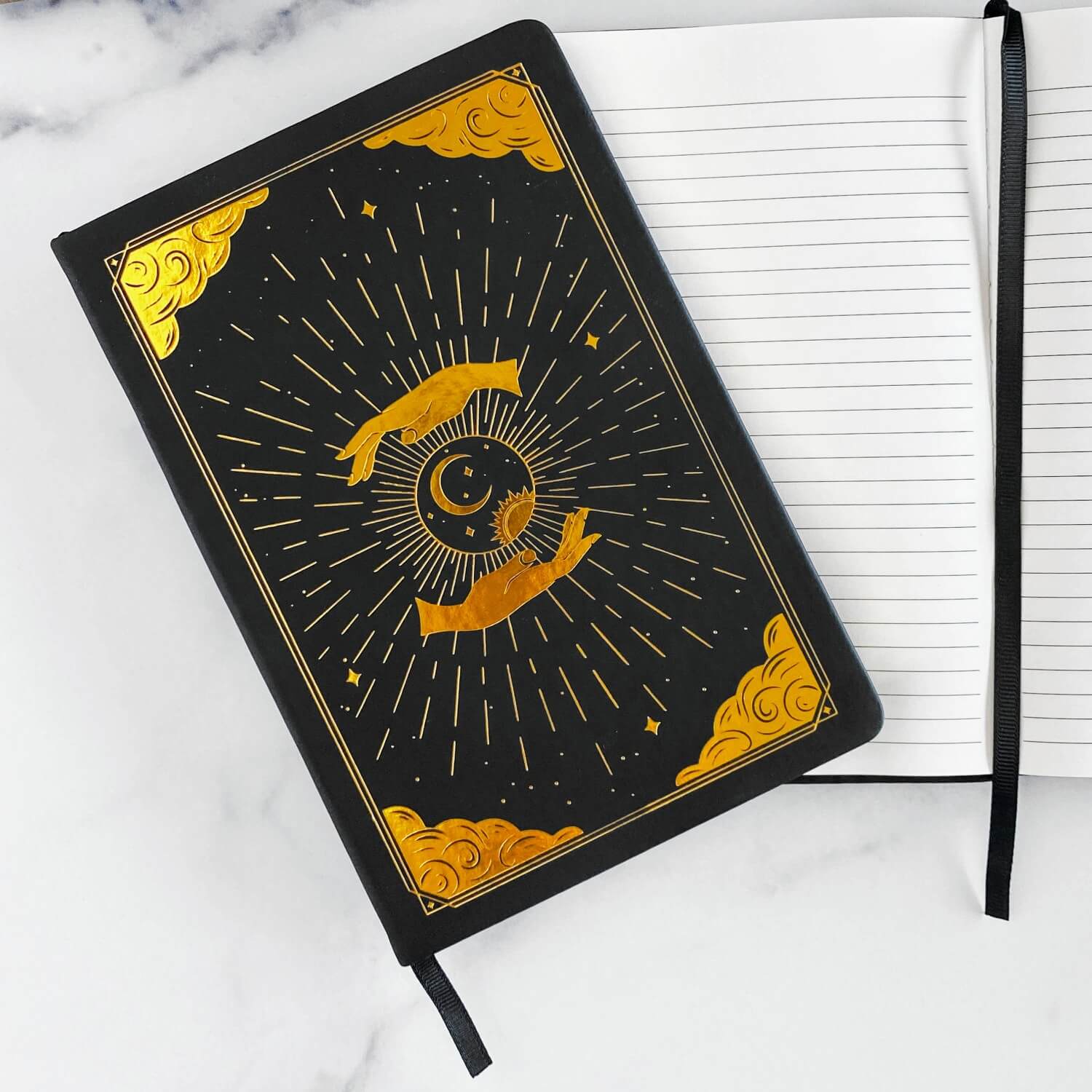 Black intention and mindfulness journal and notebook with gold celestial design on a white marble surface