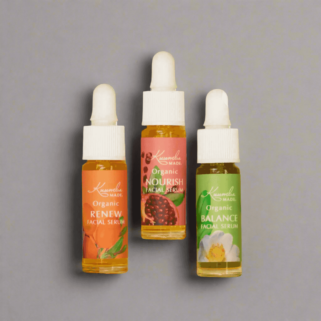 Travel-size Kuumba Made Botanical Facial Serum Discovery Gift Set with Balance, Nourish, and Renew serums on neutral gray background.