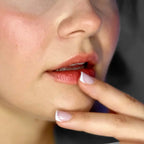 A close up of a fair skinned model wearing River Organics long wearing rouge red organic tinted lip balm.