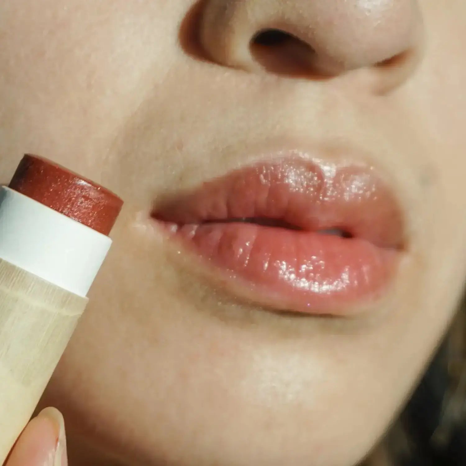close up of long wearing rouge red organic tinted lip balm on lips with model holding it's plastic-free paper tube