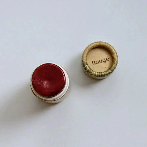 Close up of long wearing rouge red organic tinted lip balm in plastic-free paper tube by River Organics