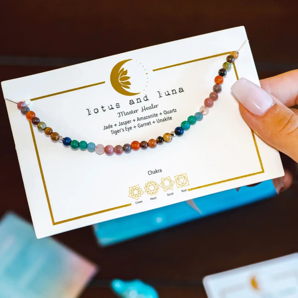 A multicolor beaded chakra healer necklace displayed on a white card labeled 'lotus and luna Master Healer'