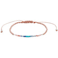 A delicate peach-pink beaded bracelet with a central row of multicolor beads in shades of blue, green, and purple.