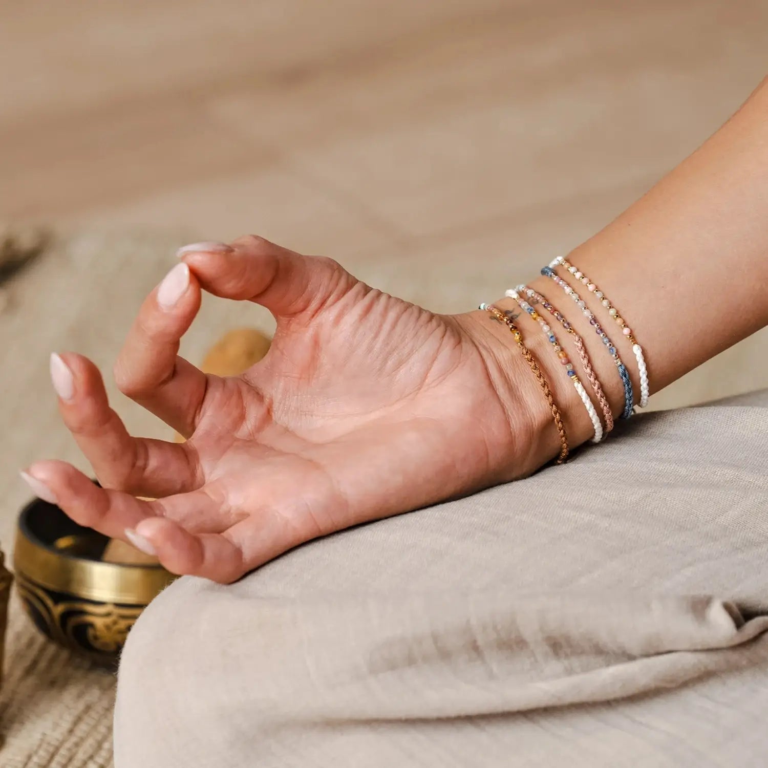 A Hand in Lotus Mudhra Wearing a Collection of Lotus and Luna Namaste Yoga Bracelets on Wrist
