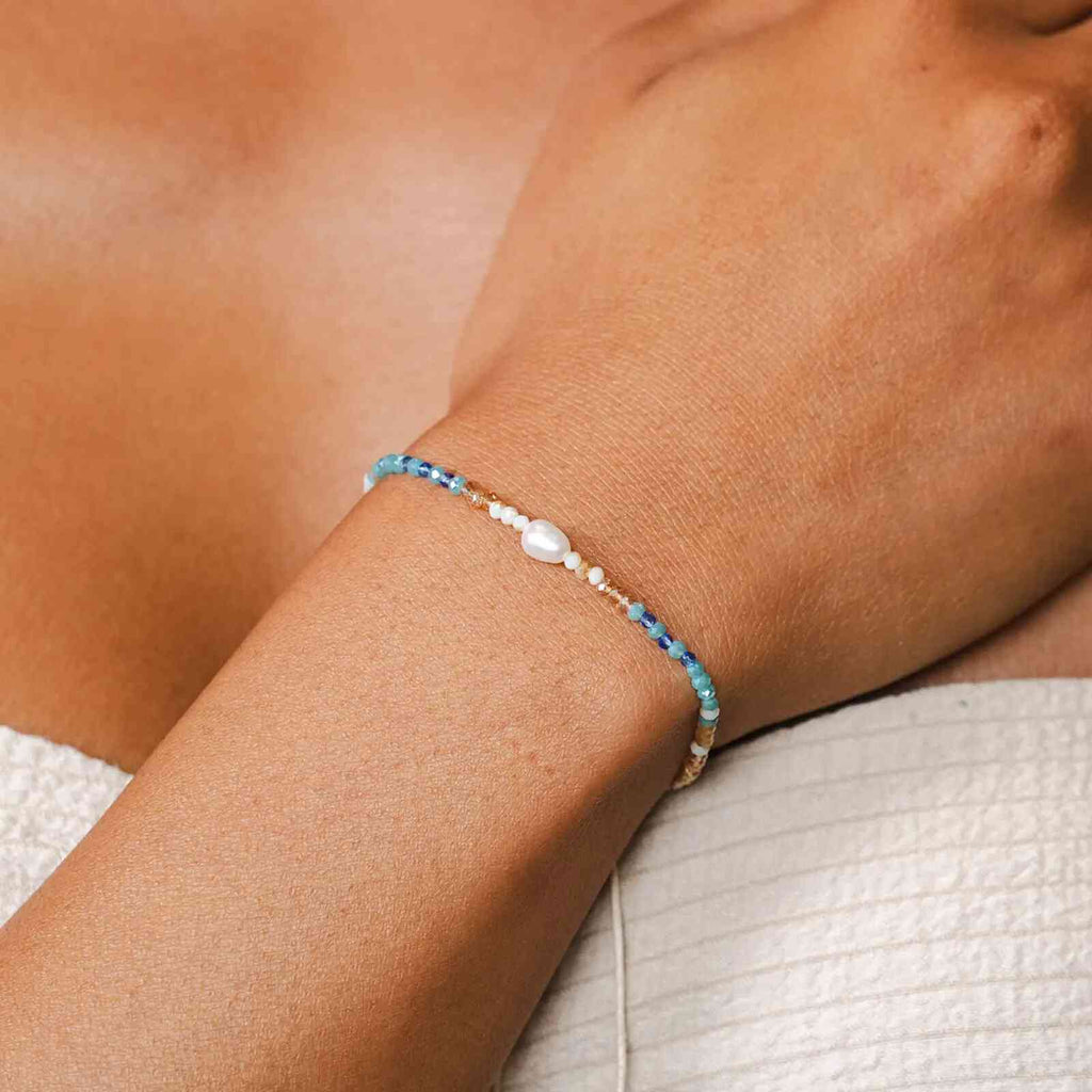 Lotus and Luna Make Waves Goddess Bracelet with Pearl and Crystals shown on wrist, featuring blue, teal, and gold beads in a boho style.