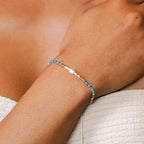 Lotus and Luna Make Waves Goddess Bracelet with Pearl and Crystals shown on wrist, featuring blue, teal, and gold crystals.