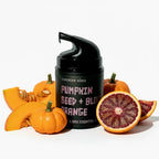 Black pump lotion bottle with pumpkin seed and blood orange text, surrounded by pumpkins and an orange on a white background.