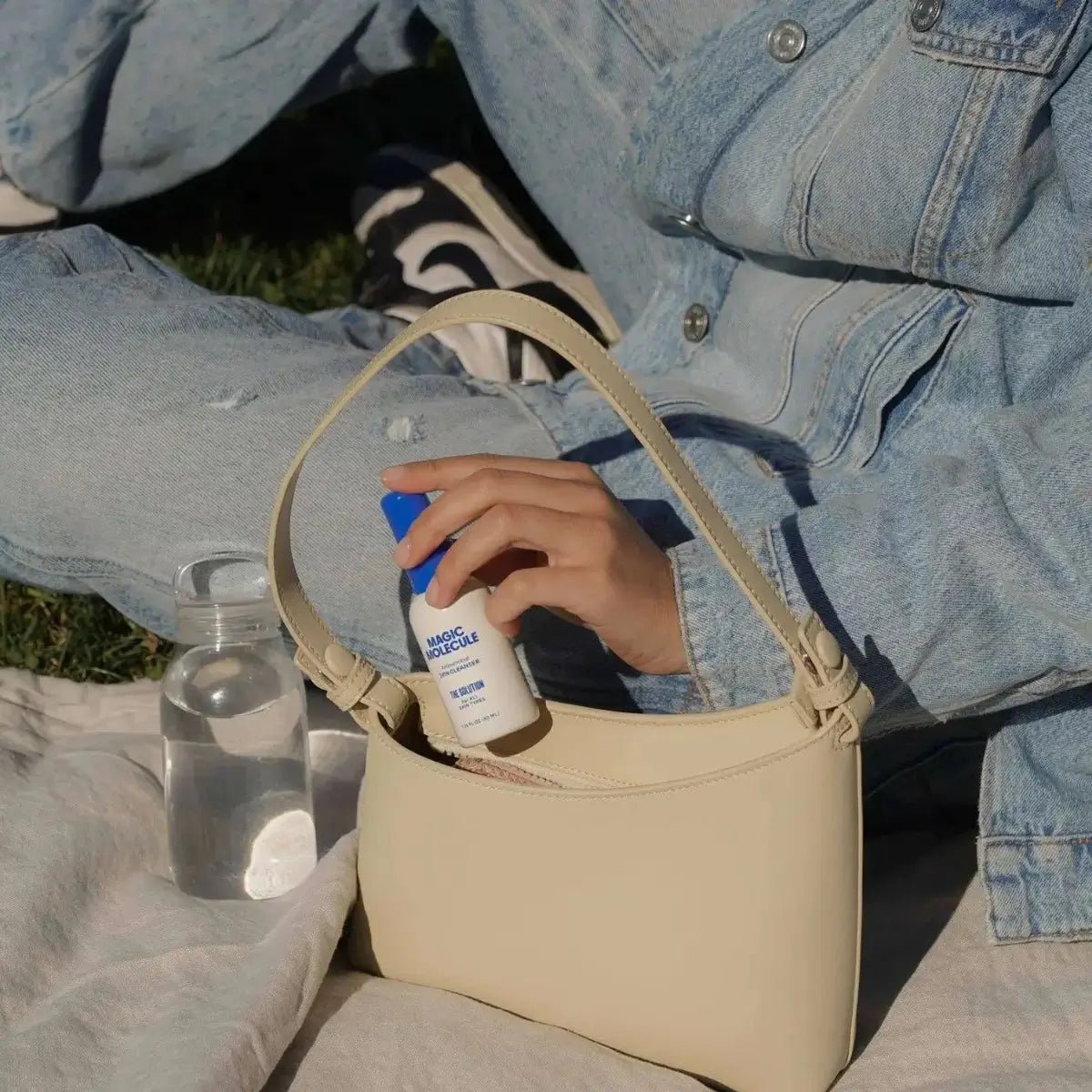 a woman putting a travel size bottle of magic molecule skin spray in her handbag