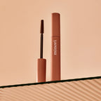 a tube of minori mother of lashes mascara in brown shown with it's lengthening and defining bristle brush