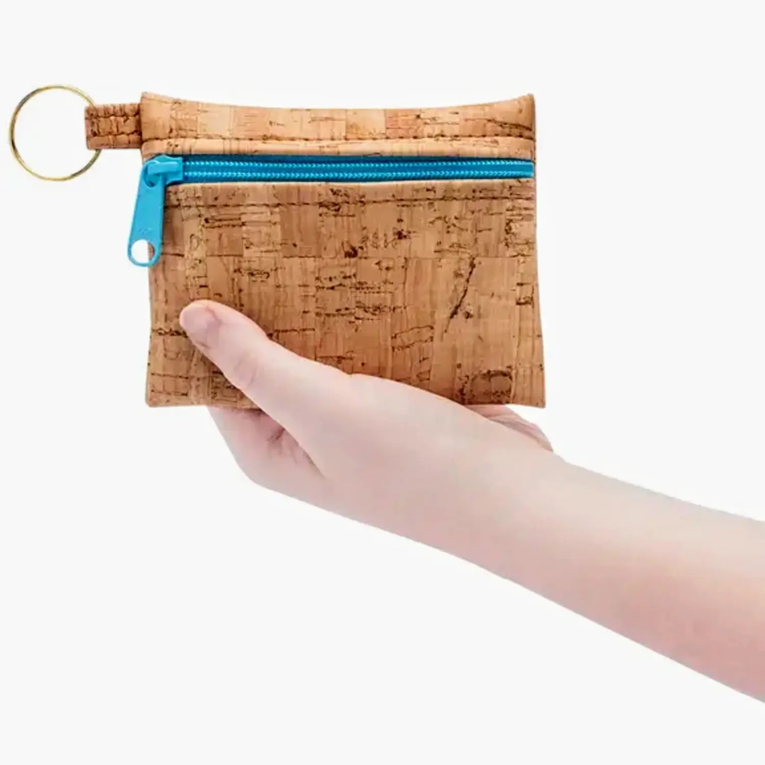 Cork keychain pouch with blue zipper held by a hand on a white background