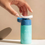 Hand holding a cotton pad to use nuria hydrate refreshing micellar water with built in pump dispenser