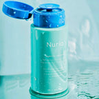 Micellar water in a blue and green bottle with 'Nuria' branding on a light blue background