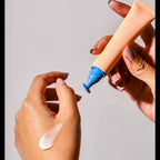 Hand applying Nuria Eye Cream with a drop of cream on the skin, demonstrating its lightweight and nourishing consistency.