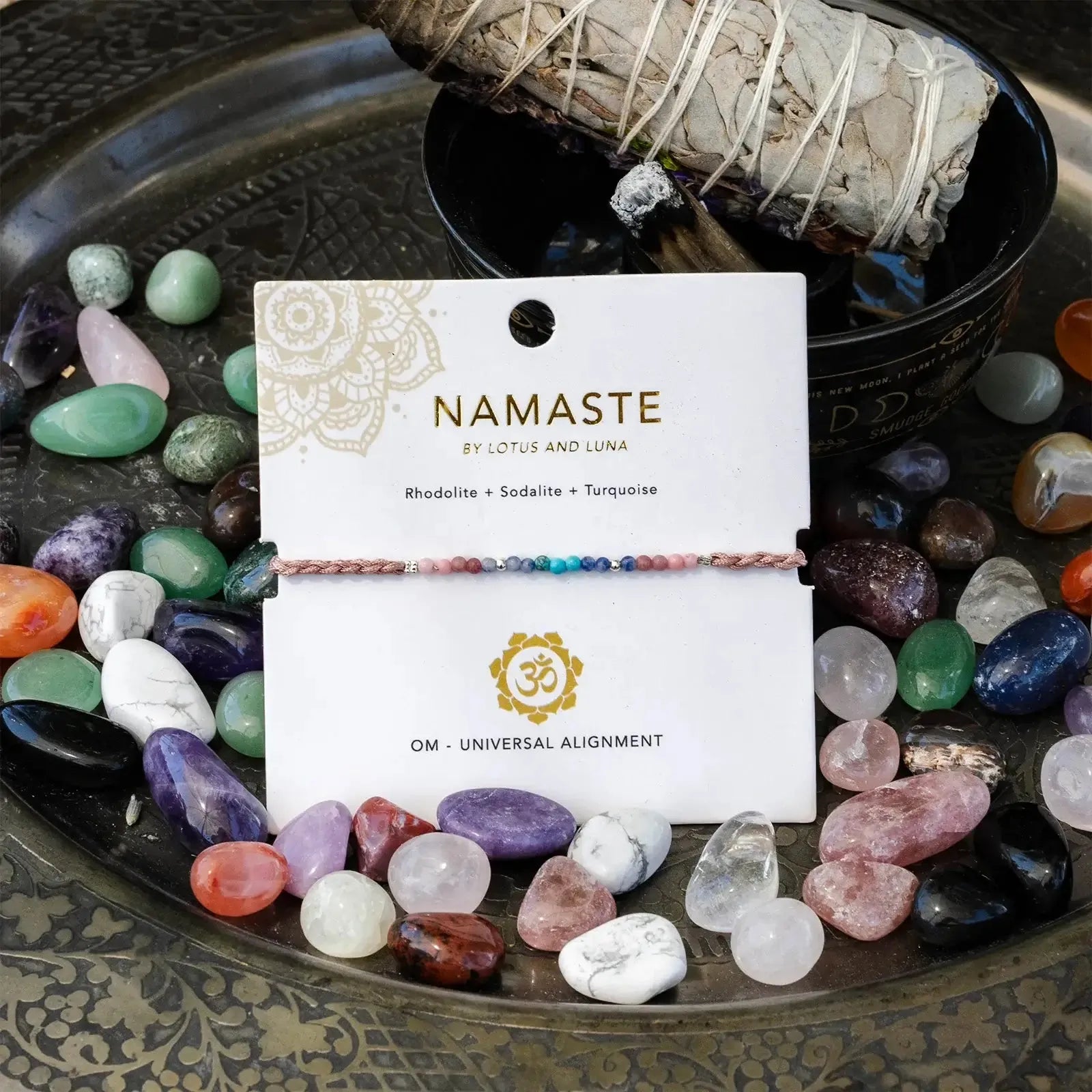 Om Mantra Bracelet - Gemstone Yoga Bracelet with rhodolite, sodalite, and turquoise beads on display among healing crystals. Adjustable fit for spiritual balance.