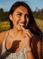 A woman applying Organic Red Tinted Lip Balm to her lips.