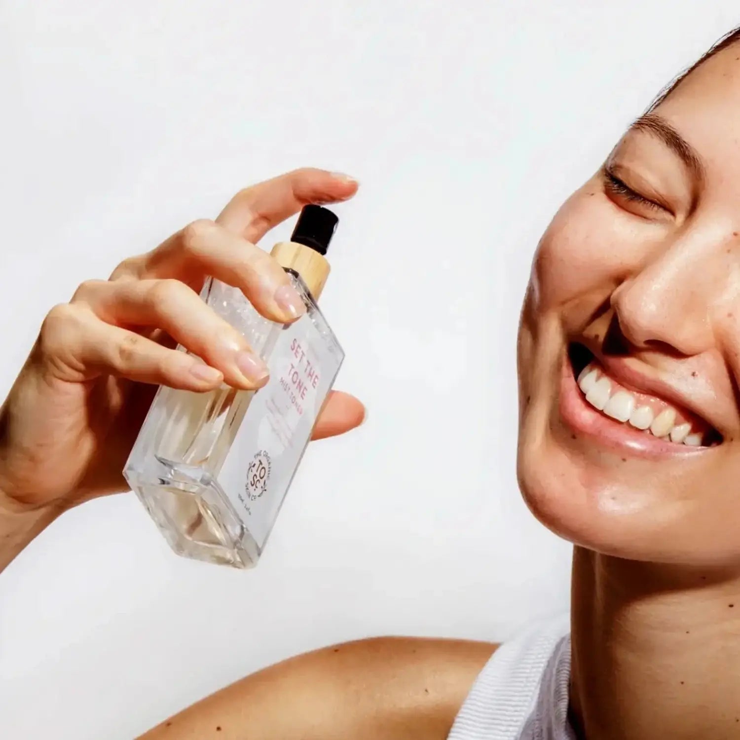 a woman spraying rosewater toner on her face