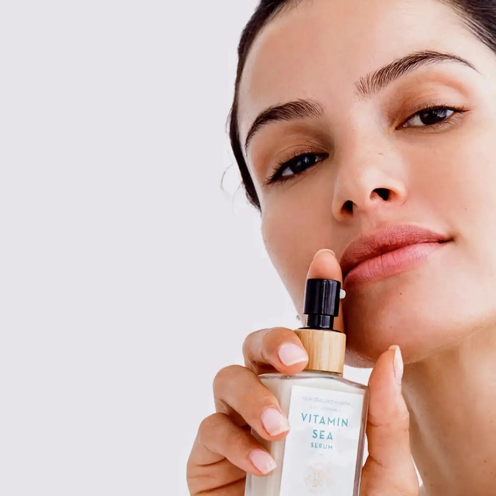 a woman holding a bottle of the organic skin co vitamin sea serum