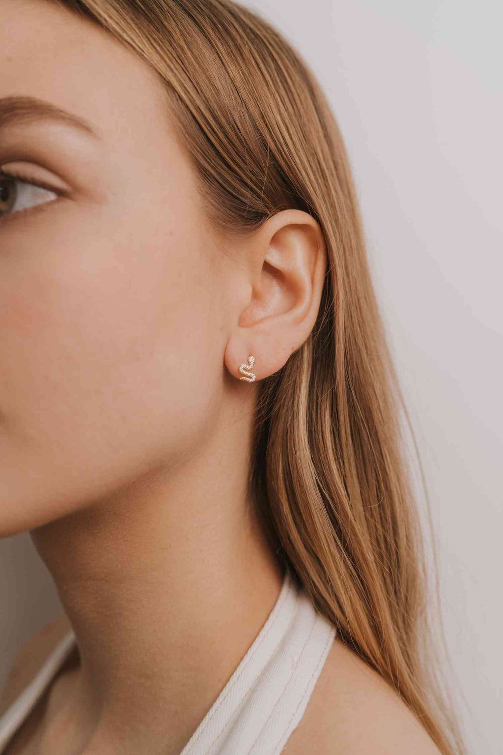 a close up of a person wearing a pair of gold snake earrings