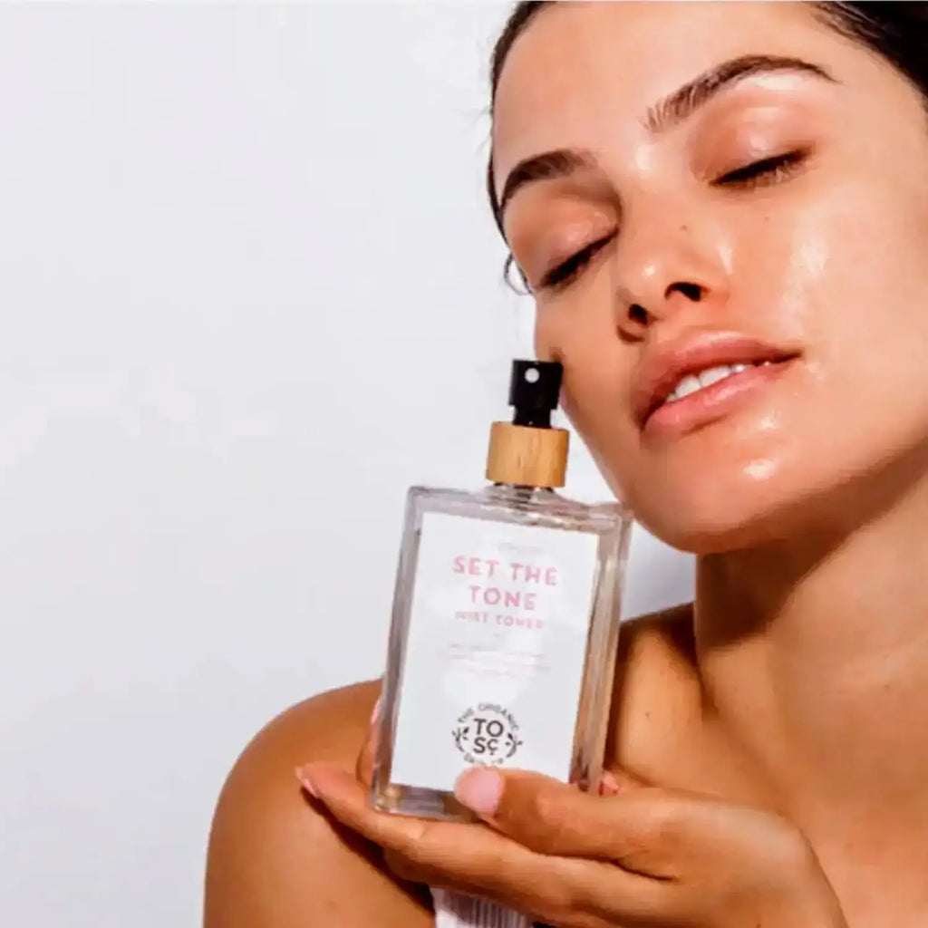 a woman hold a bottle of the Organic skin Co set the tone rose mist toner