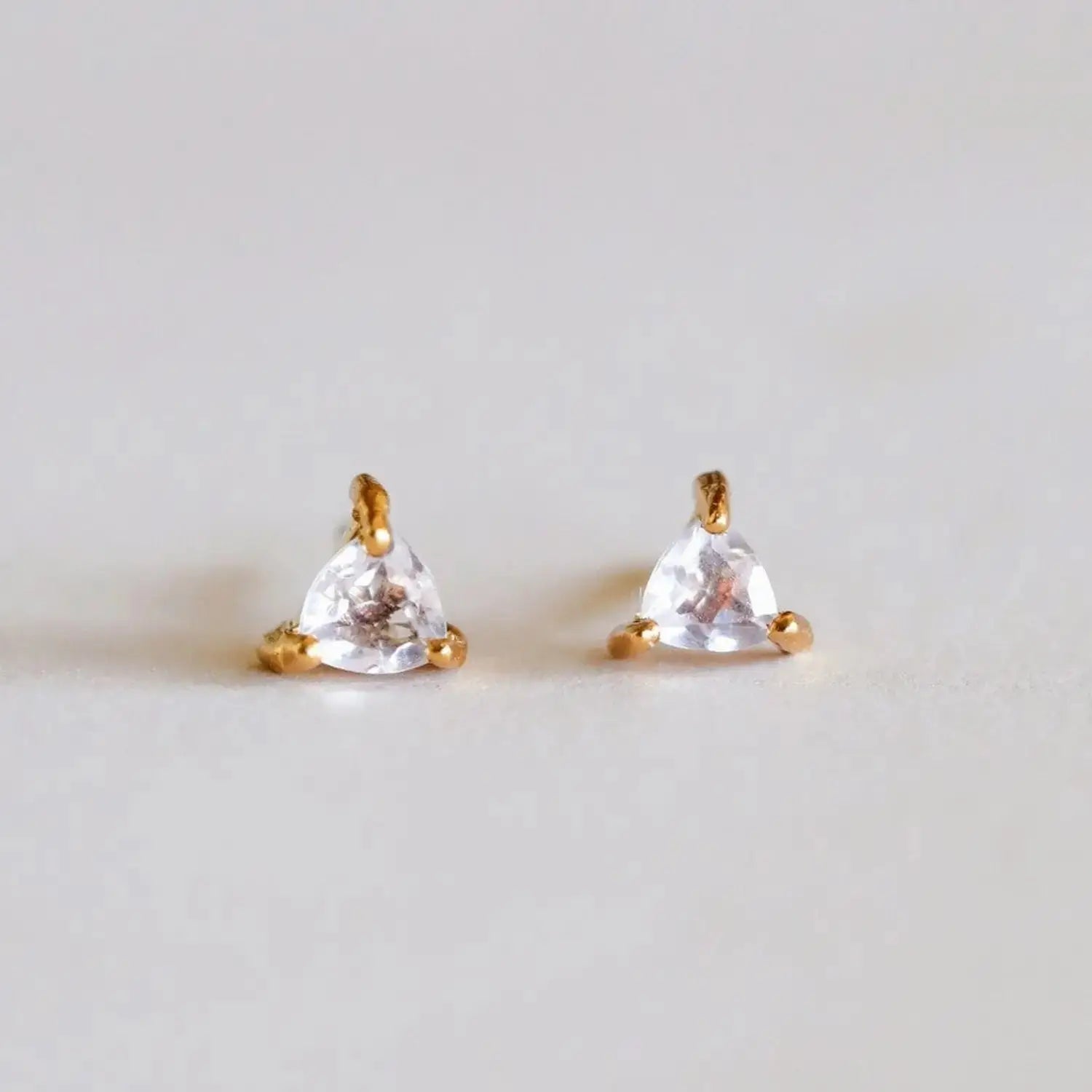 Rose Quartz earrings featuring triangular gemstone studs set in 18k gold plating. Elegant and symbolic of love, perfect for gifts or personal style.