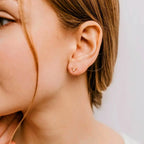 Rose quartz pink gemstone earrings in a triangle stud design shown on a model.