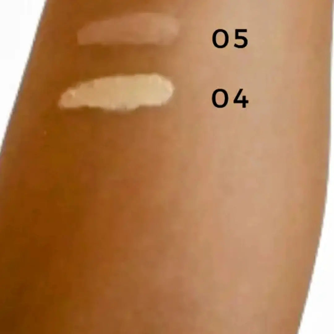 Two swatches of cream concealer on a person's arm with labels '05' and '04'.