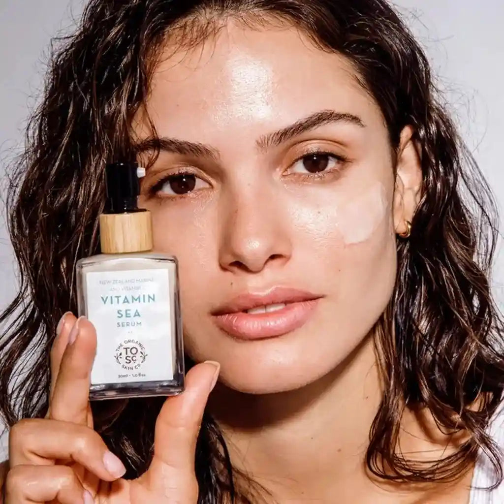 a woman holding up a bottle of organic skin co vitamin sea face serum
