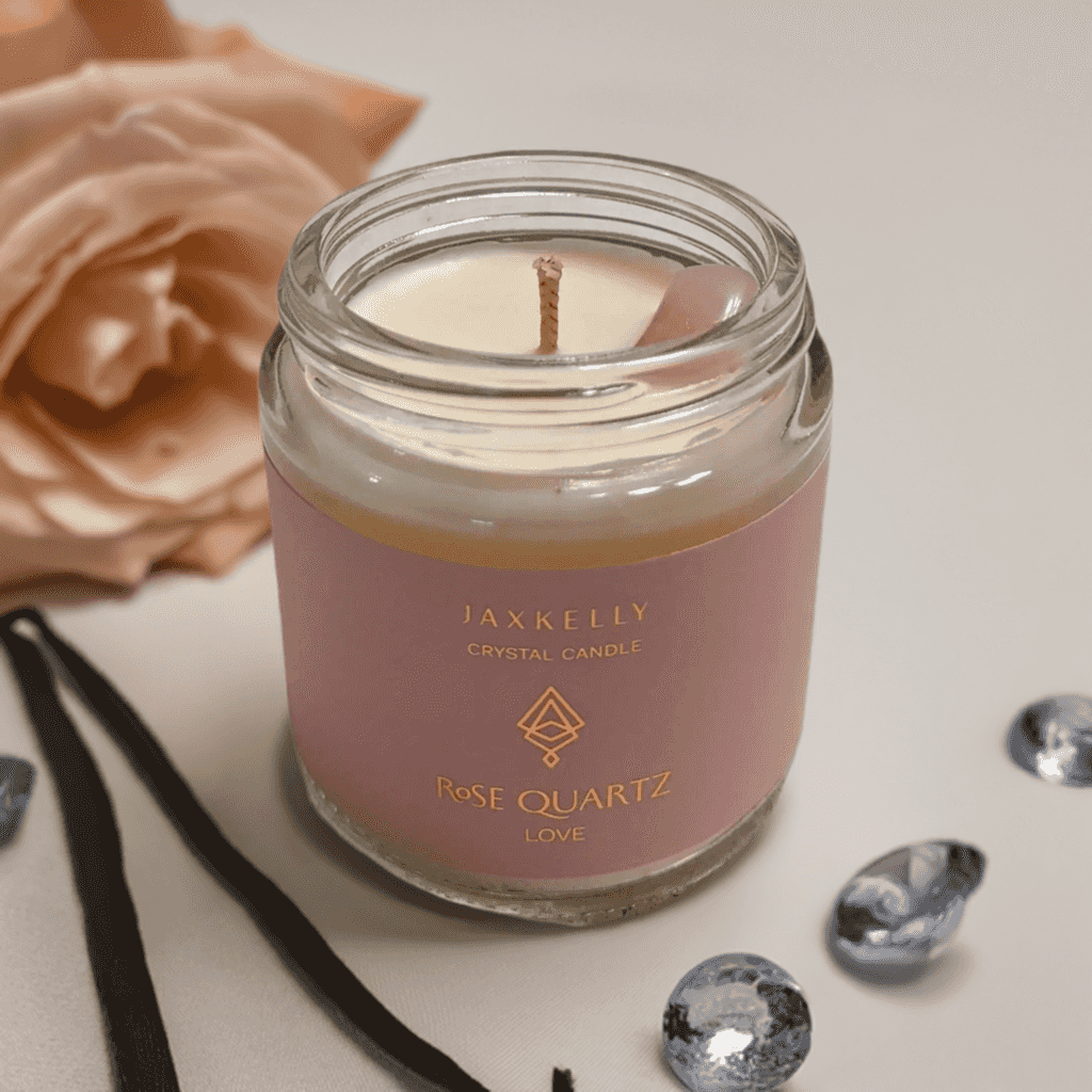 a pink JaxKelly crystal candle sitting next to a pink rose