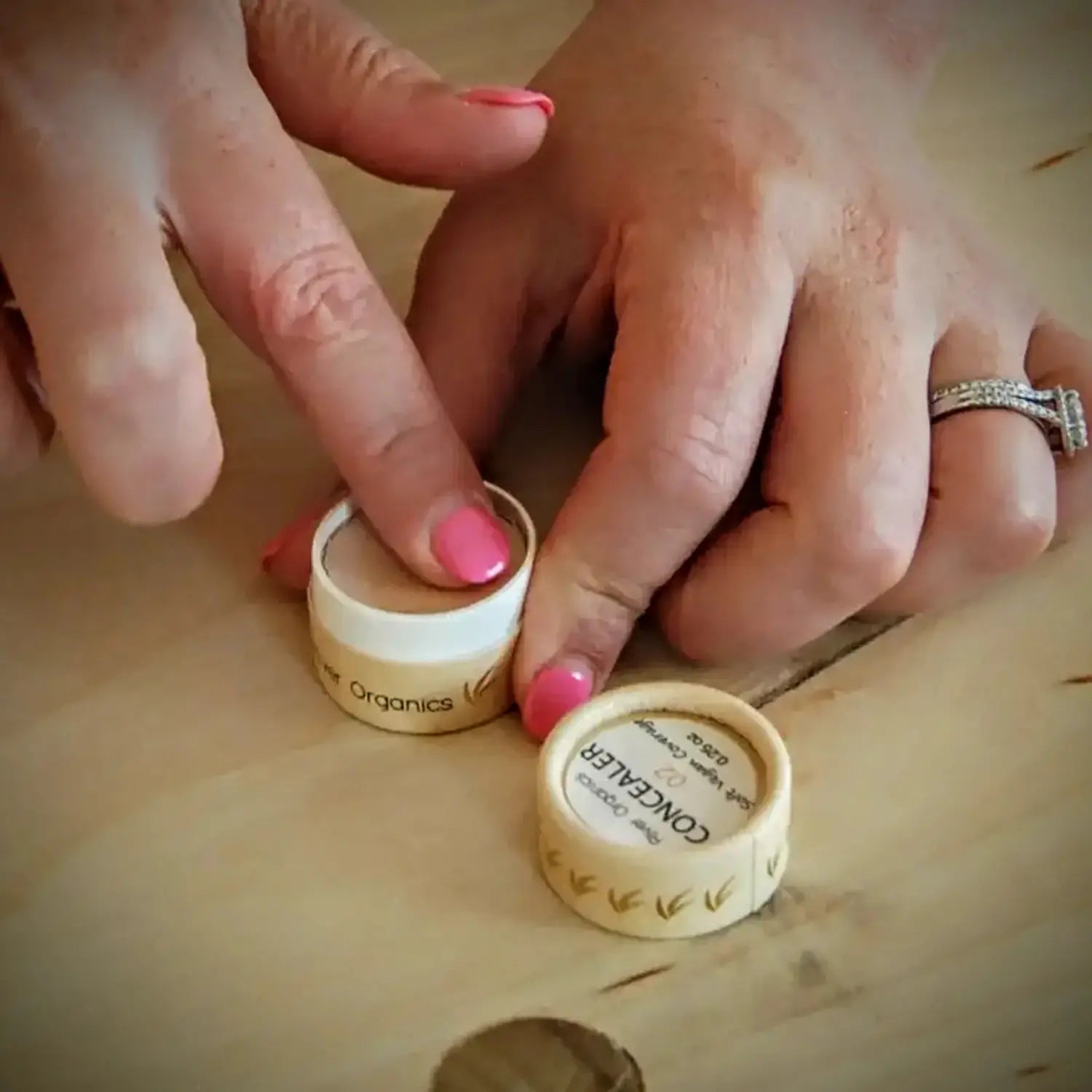Close-up of hands interacting with small containers on a wooden surface