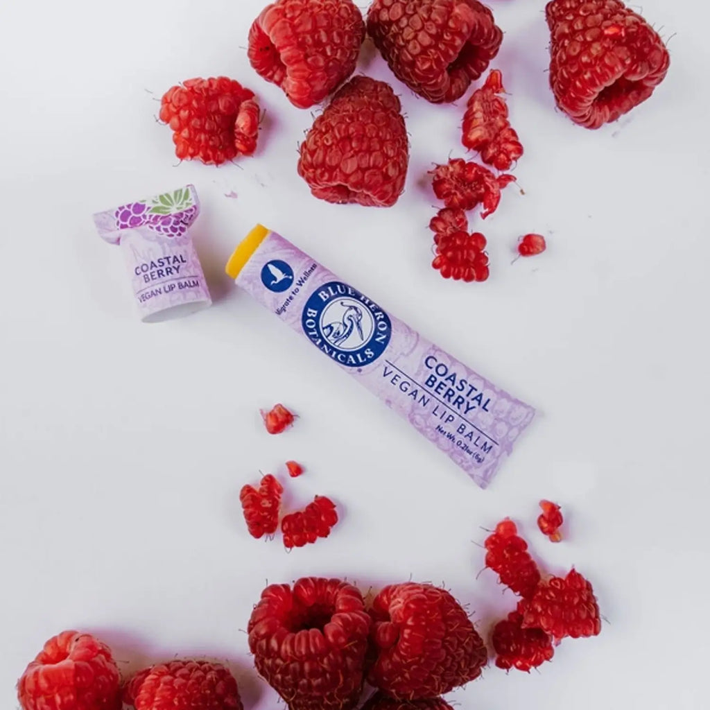 tube of vegan lip balm with SPF and red raspberry oil on table with red raspberries