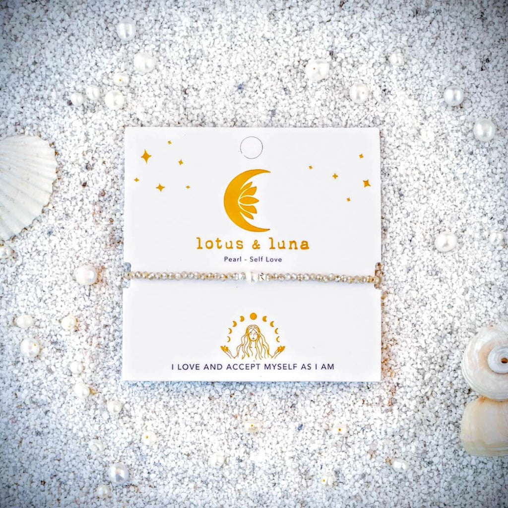 Pearl and Crystal Bracelet on a card with 'lotus & luna' branding on sand surrounded by seashells.