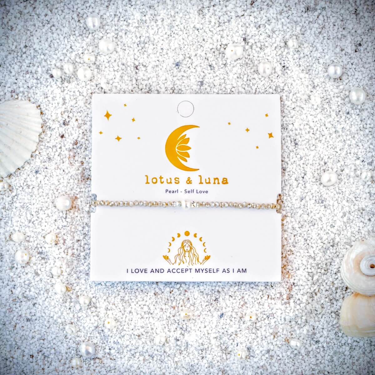 Pearl and Crystal Bracelet on a card with 'lotus & luna' branding on sand surrounded by seashells.