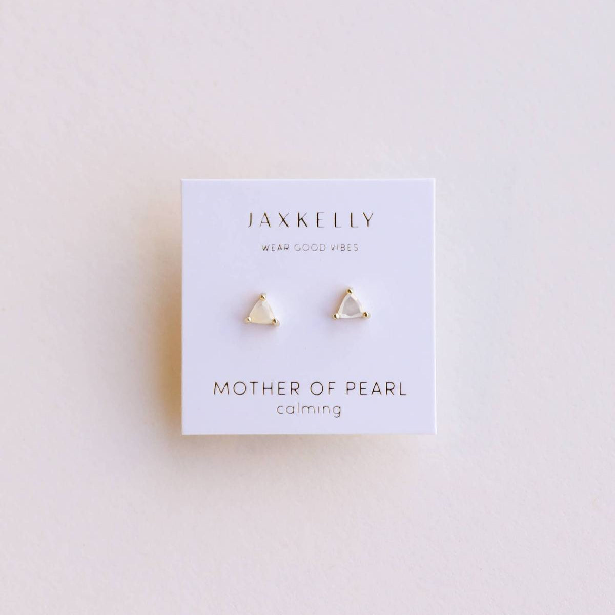 Jax Kelly Earrings - Mother of Pearl Gemstone Studs. White mother of pearl and yellow gold  mini energy gem gemstone stud earrings in a triangle shape on jewelry card.